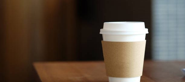 Coffee paper cup on wood table in coffee cafe.